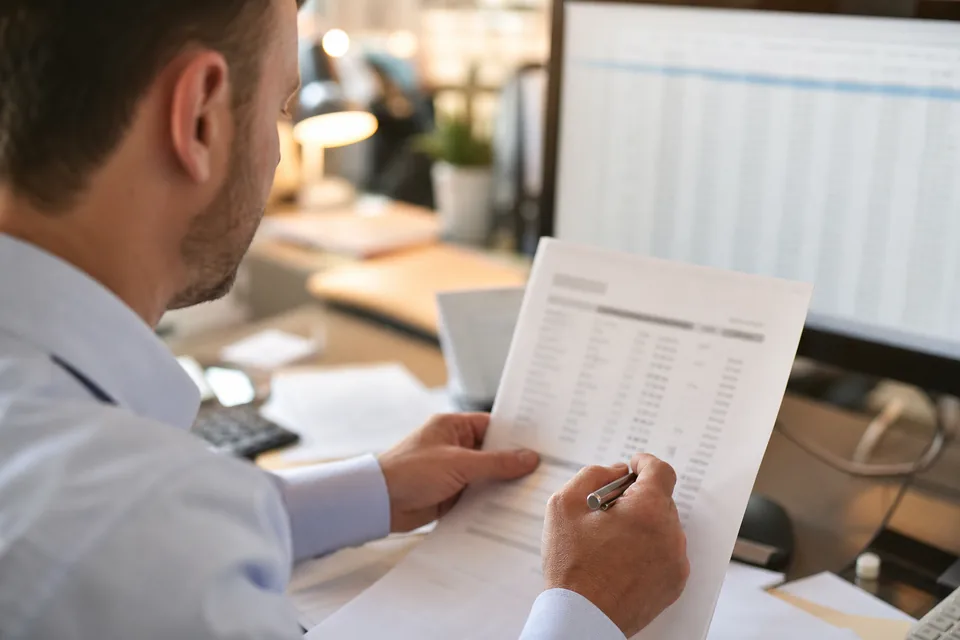 Accountant checking invoice line totals against spreadsheet rows